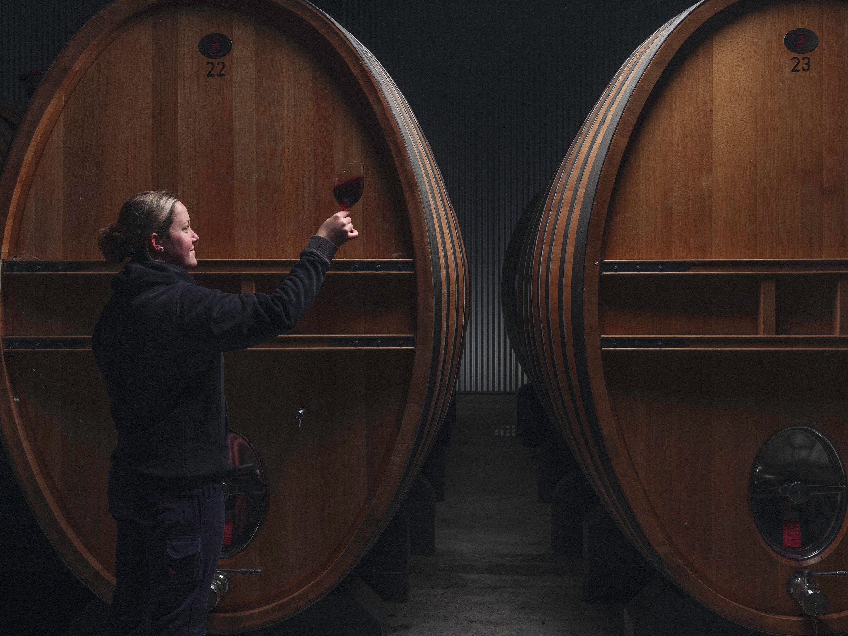 Person inspecting a wine barrel in a dimly lit cellar