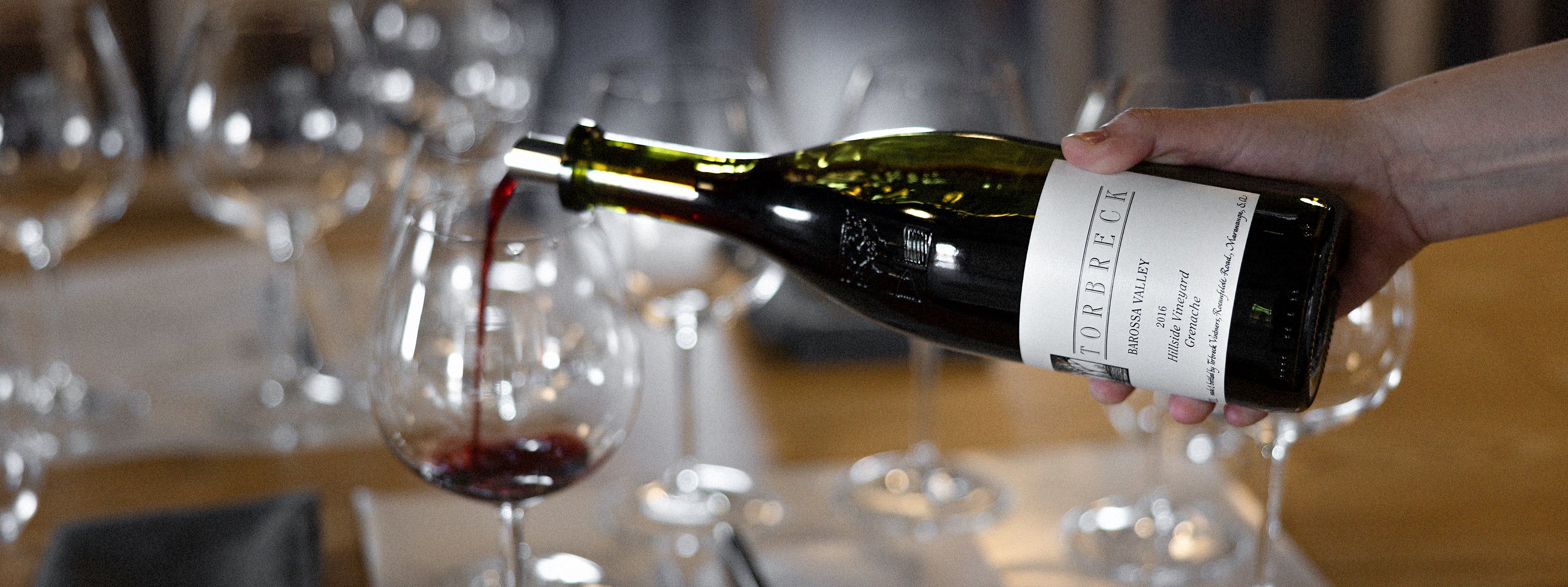 Hand pouring wine from a bottle into a glass with blurred background