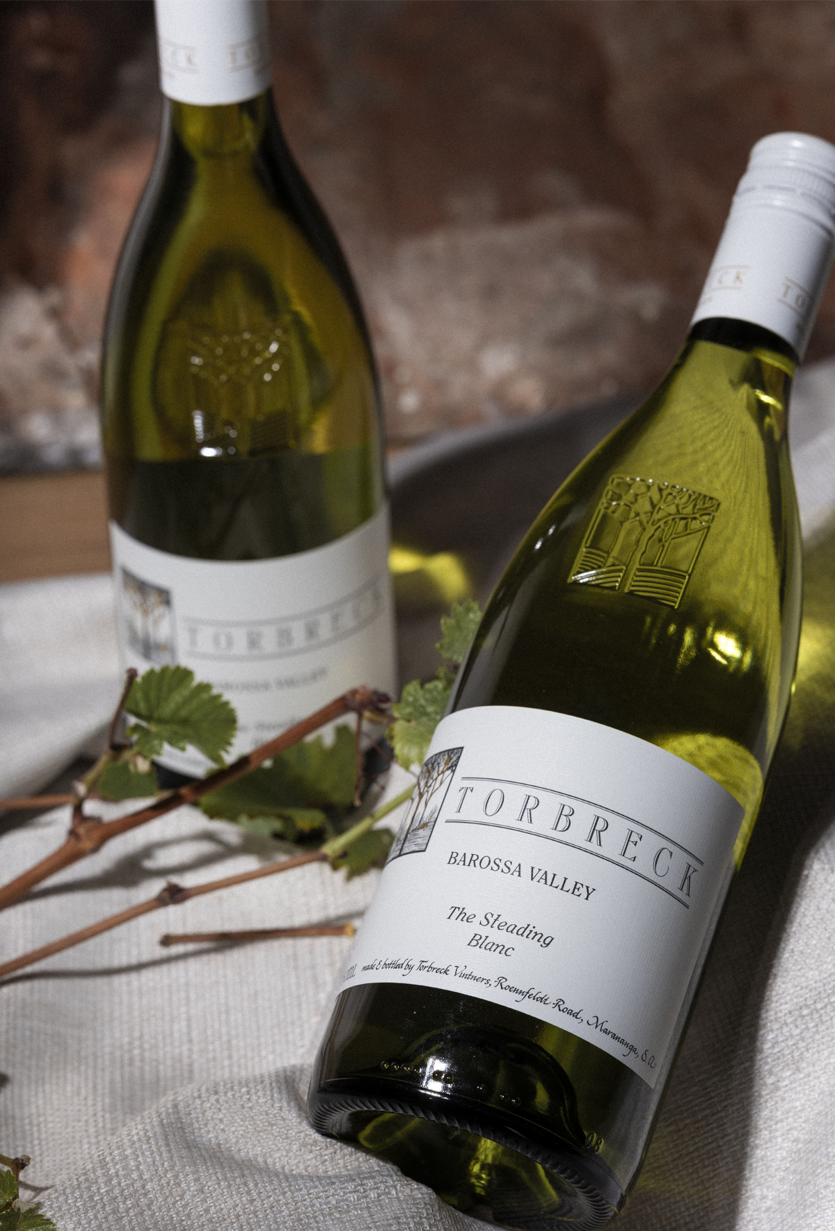 Two bottles of Torbreck wine on a textured surface with a blurred background