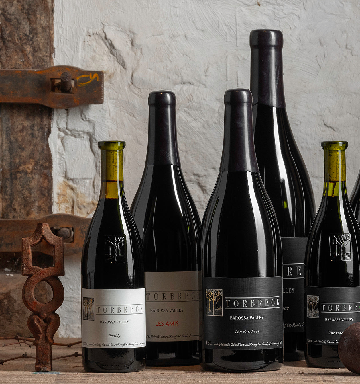 Collection of Torbreck wine bottles against a rustic stone wall.